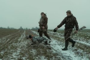 Cazadores caminando con un perro en un campo nevado