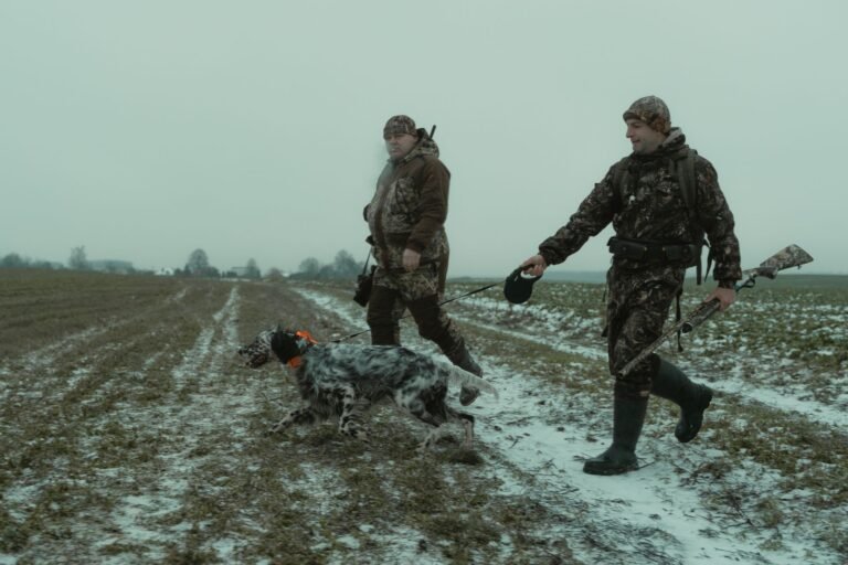 Cazadores caminando con un perro en un campo nevado