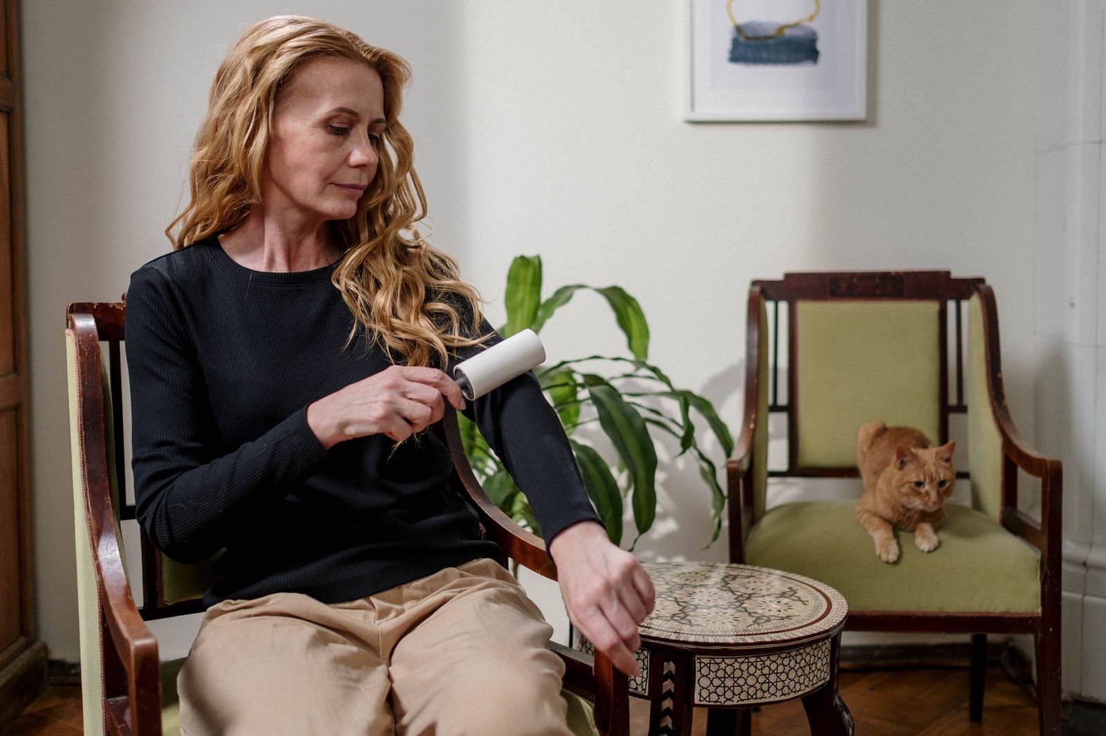 Mujer usando un rodillo quitapelos en su ropa junto a un gato